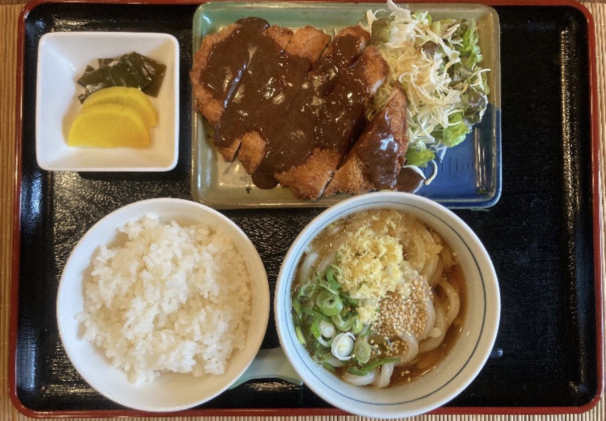 ソースのかかったカツと、ごはん、うどん、お漬物がそろったお膳